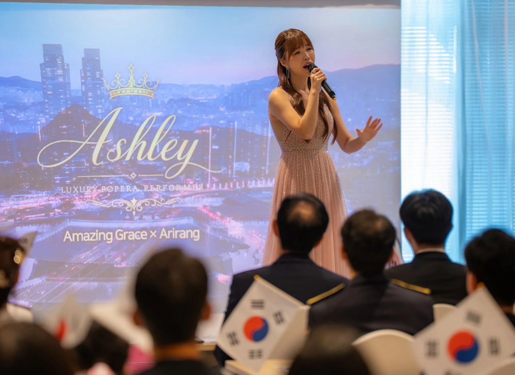 Ashley singing on stage in an evening dress, with an audience in the foreground